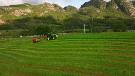 Der-Grüne-Traktor-Zieht-Den-Roten-Mähaufbereiter-Und-Schneidet-Das-Erntegut-Für-Die-Silage