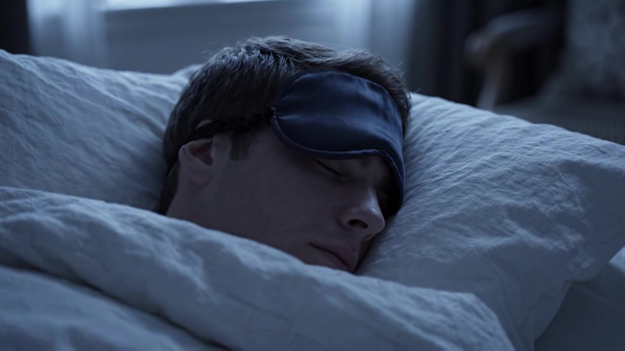Een vredige nacht: Een man die geniet van een rustgevende slaap terwijl hij een slaapmasker draagt, ondergedompeld in sereniteit en comfort onder knusse beddengoed.