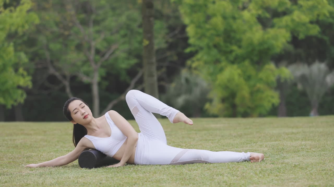 Gesunder Fitness-Lifestyle: athletische junge Frau in Sportkleidung macht Yoga-, Dehn- und Meditationsübungen mit Namaste-Geste, während sie im grünen Park Achtsamkeitsatmung trainiert und meditiert
