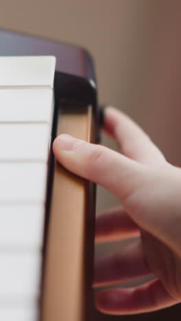 child hand presses power button on electronic piano. girl prepares to play modern musical instrument. hobby and leisure closeup on blurred background
