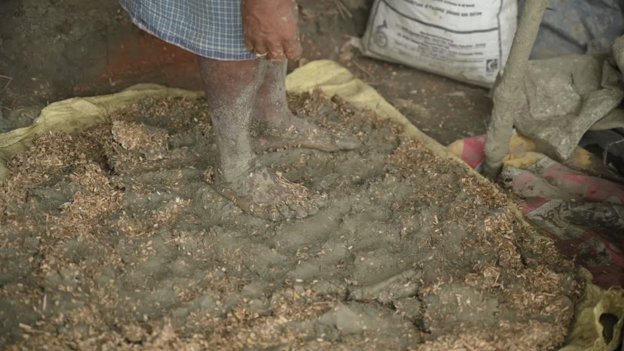 조각품 을 만들기 위해 점토 를 부수기 위해 발 을 사용하는 가난 한 노동자