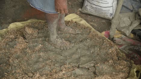 poor labour using feet to smash clay for sculpture