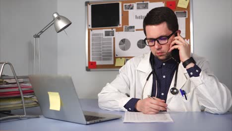 doctor talking on phone and working on laptop