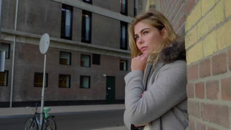 serious woman poses against a brick wall