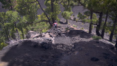 Back-view-of-european-young-man-red-shirt-and-grey-backpack-running-downhill-in-volcanic-landscape