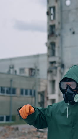 human survivor standing alone in ruined place. guy in the gas mask and safety clothes against the background of abandoned building. apocalypse concept. vertical video