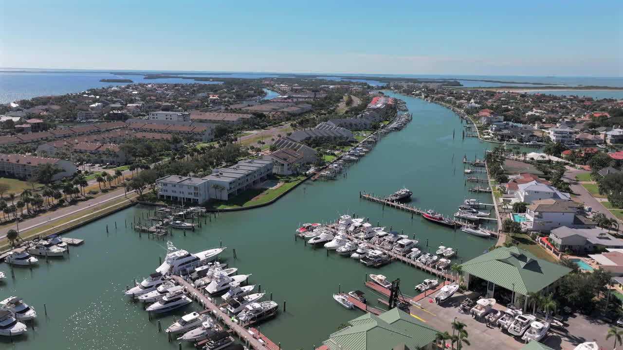 Aerial drone view of luxury waterfront condos and marina along Pine Key Cutoff in Tierra Verde, Saint Petersburg, Florida, showcasing boats, docks, and coastal residential living