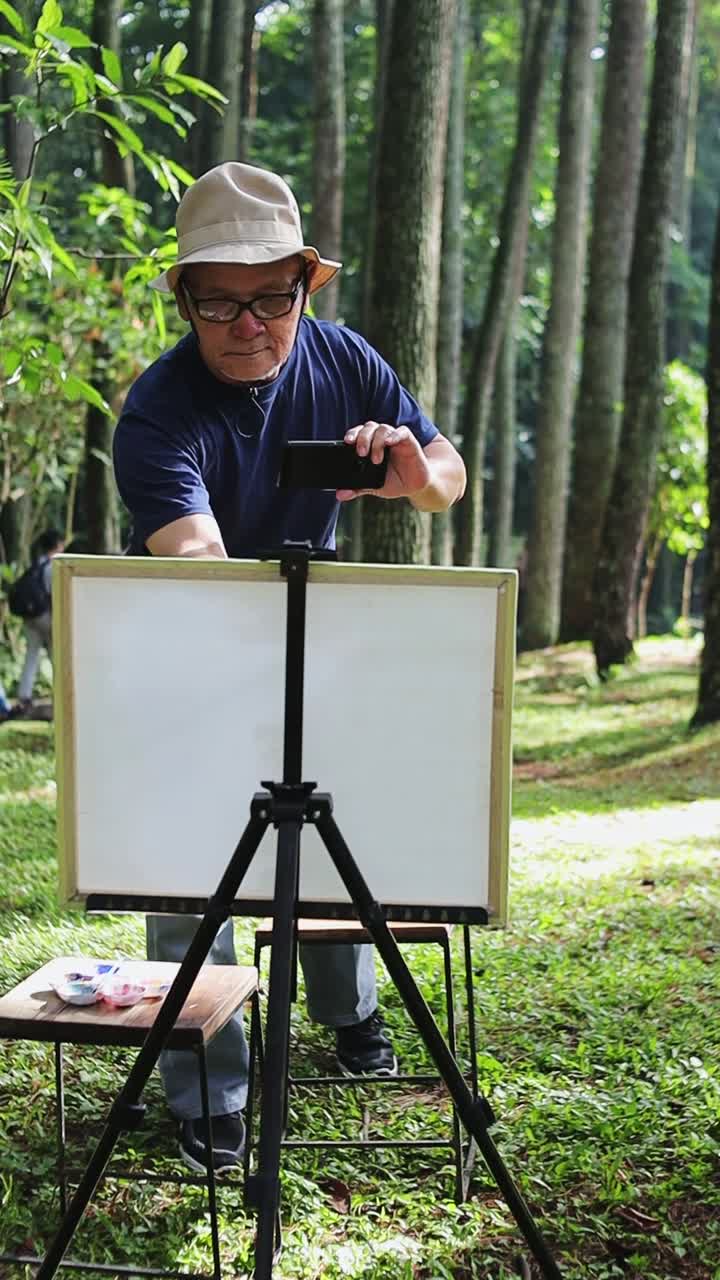 Artist capturing forest inspiration with smartphone before painting in serene woodland setting