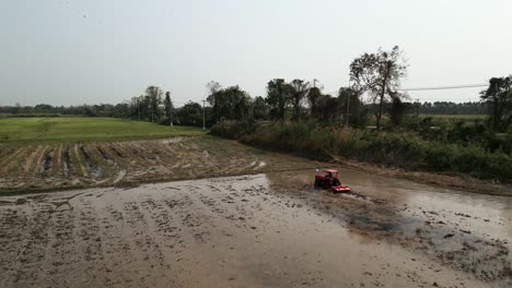 tractor cultivating a flooded rice field