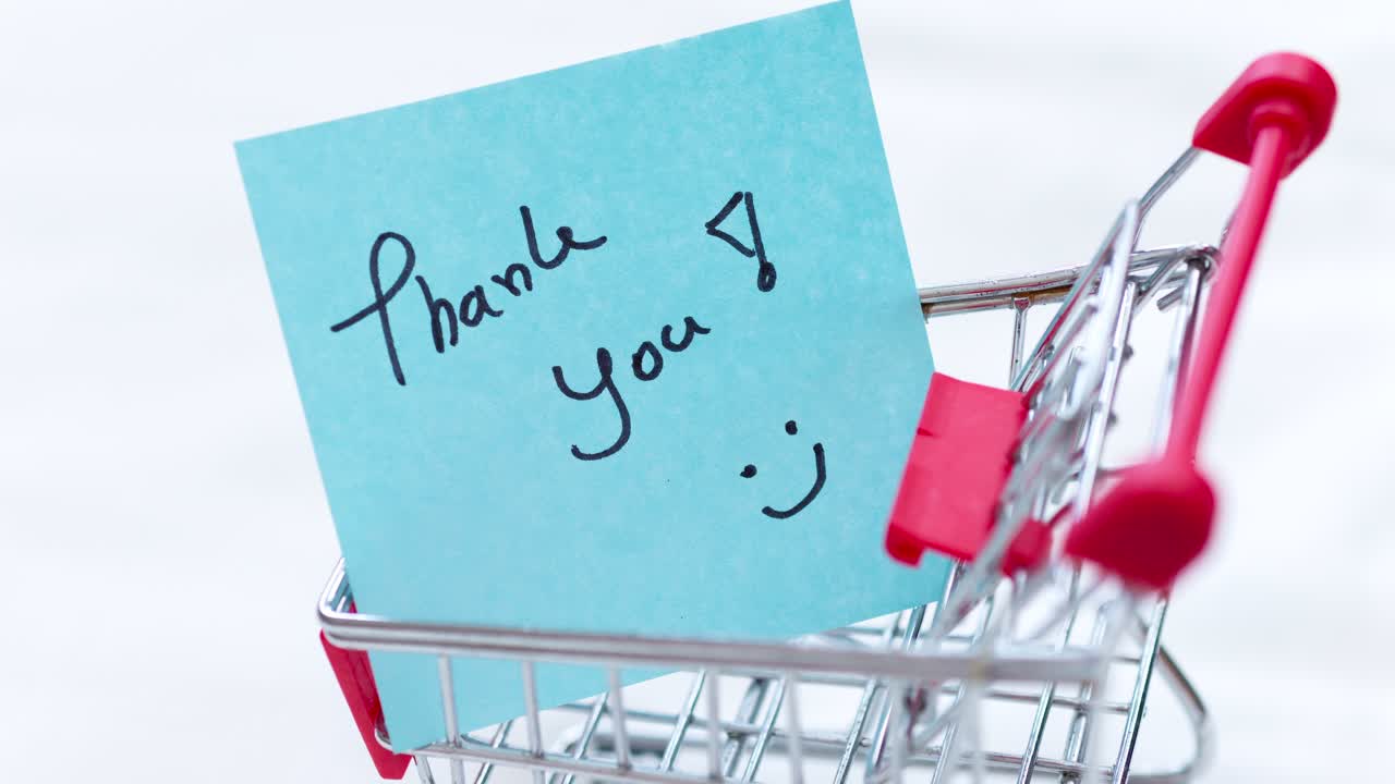 A heartfelt thank you note resting in a shopping cart emphasizes appreciation in retail.