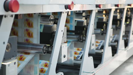 long metallic body of servo automated print labeling machine with turning cylindrical rollers and drums on sheet of paper