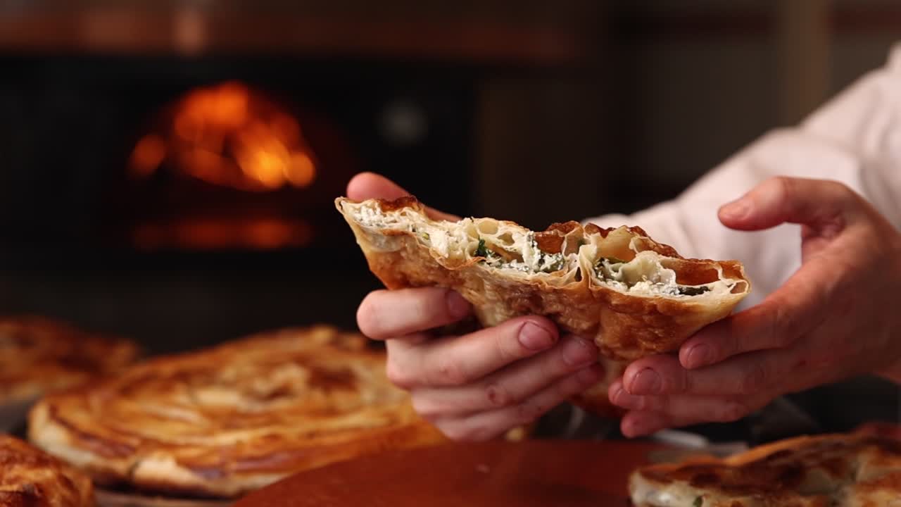 Hands Holding Freshly Baked Savory Pastry with Cheese and Herbs