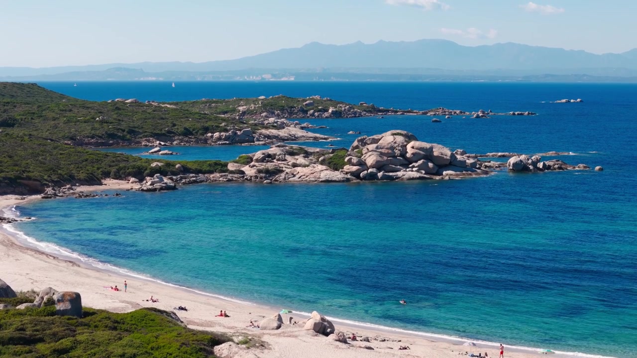 Veduta aerea di una tranquilla spiaggia sarda con mare turchese e costa rocciosa