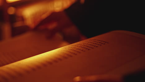 person reading an old book by candlelight