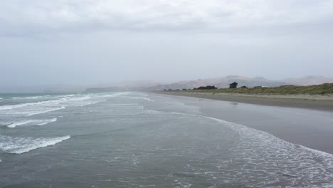 aerial shot flying over waves towards a dark stormy sky.