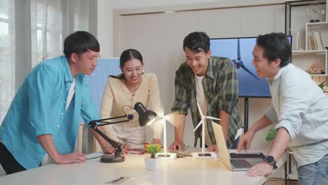 happy asian engineers group celebrating succeed testing the wind turbine at the office