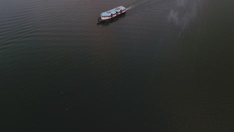 Reveal-drone-footage-from-the-boat-traveling-int-the-lake-towards-the-hotel