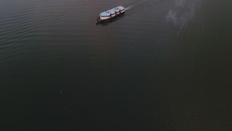 Enthüllen-Sie-Drohnenaufnahmen-Vom-Boot,-Das-Im-See-Zum-Hotel-Fährt