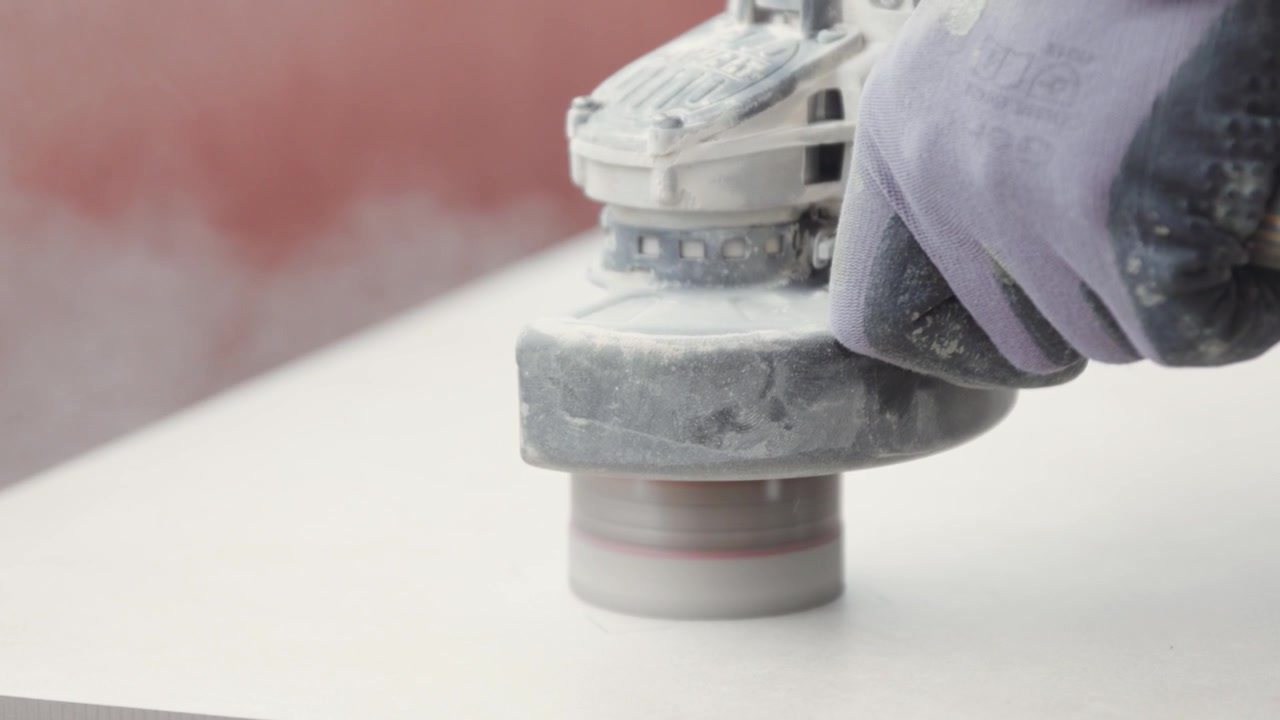 Construction worker cutting a hole in a tile with a circular power tool.