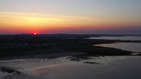 el sol dorado se eleva sobre el horizonte naranja y rosa sobre la bahía de galway, la playa de grattan durante la marea baja, galway irlanda