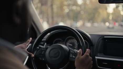 Über-Seiner-Schulter-Fährt-Ein-Glücklicher-Männlicher-Geschäftsmann-Mit-Schwarzer-Hautfarbe-In-Einer-Braunen-Jacke-Ein-Modernes-Auto-Und-Blickt-Während-Seiner-Geschäftsreise-In-Der-Stadt-Auf-Die-Straße