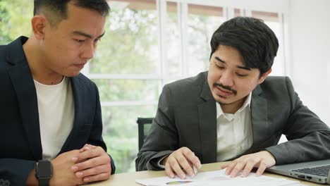 slow motion scene group of asian employee man advise and explaining to colleague about company's project on laptop screen about marketing strategy for multi ethnicity culture working concept