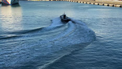 a high power motor boat turning in a harbour leaving behind a large wake wave and white bubbles on the sea surface