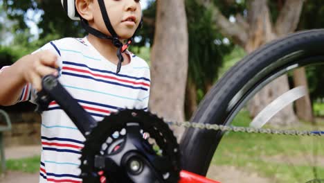 niño reparando su bicicleta en el parque