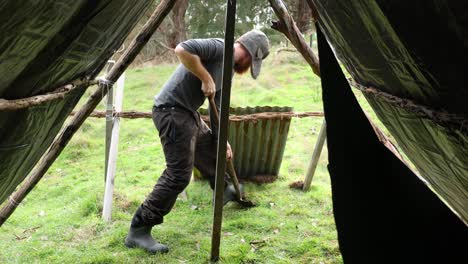 a bushman building a traditional tarp shelter and fire place in the australian bush