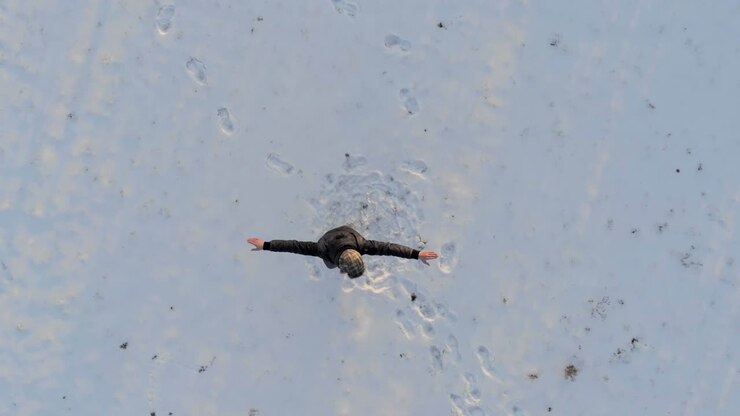 Top view of an excited man dancing alone in the snow