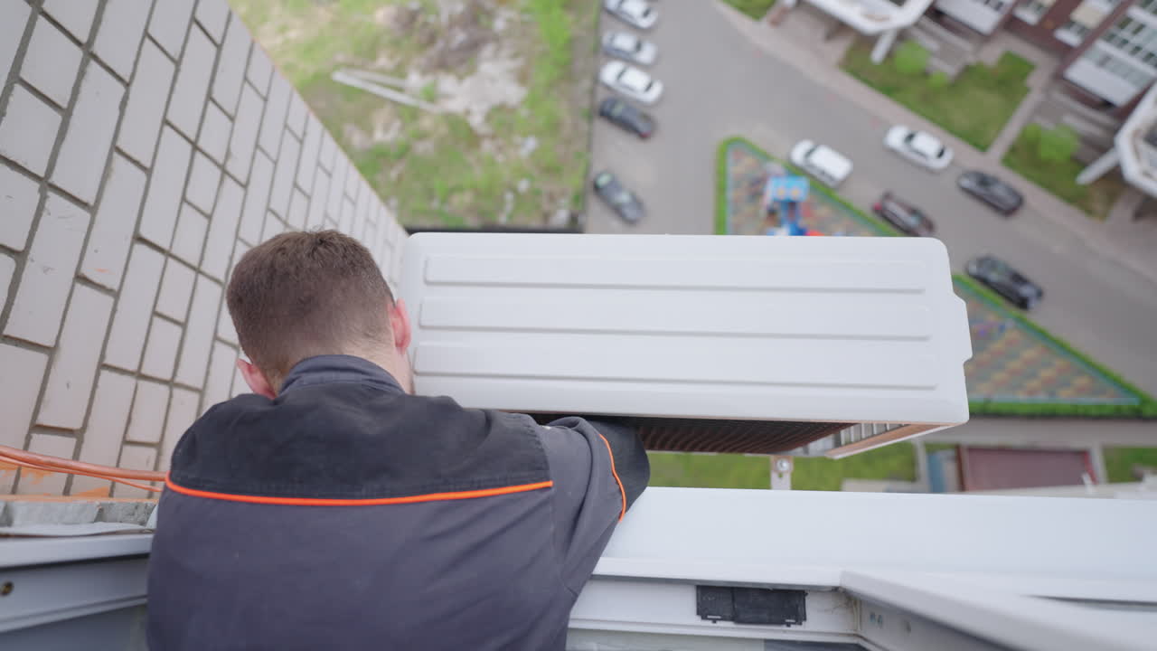 установщик устанавливает кондиционер на большой высоте в квартире