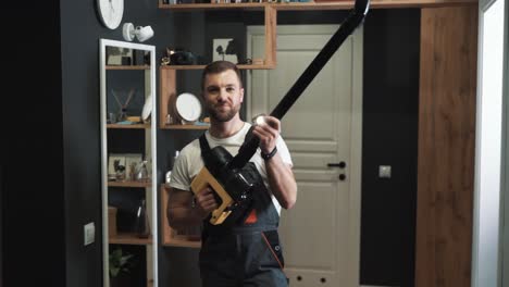 portrait of a young man in the form of a cleaner with a cordless vacuum cleaner