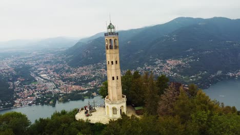 drone shot orbiting historic volta lighthouse with lake como in italy