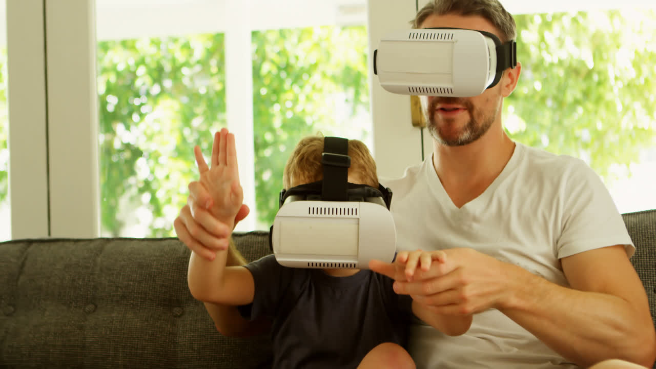 Padre e figlio che usano il visore di realtà virtuale sul divano 4k