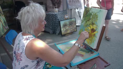 artist paints canvas with oil at public art festival