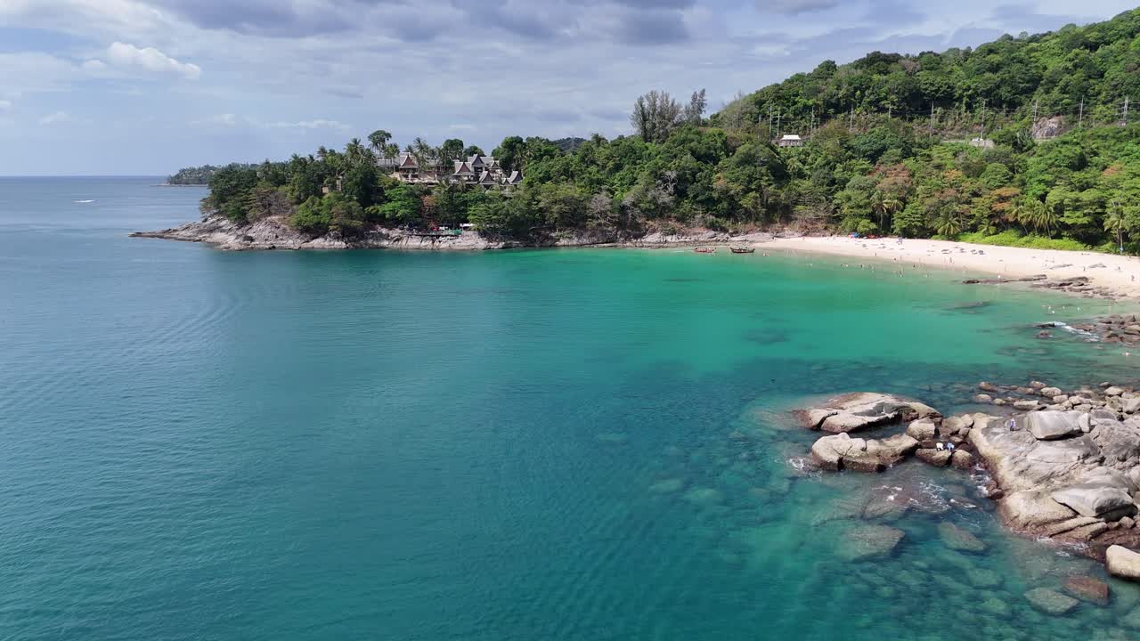Drone footage captures Phuket's vibrant coastline, showcasing turquoise waters, lush greenery, and sandy beaches under clear skies