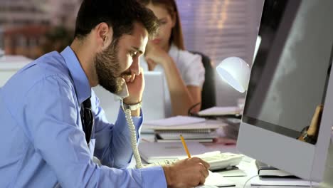 hombre de negocios hablando por teléfono mientras escribe en el diario
