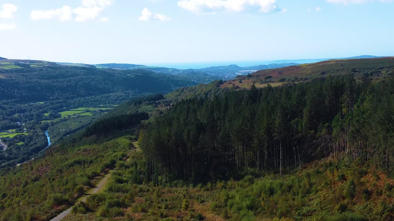 Drone View with Forest and Hiking Path Trail with River Neath in Valley Background with Ocean in Far Distance. Outdoor Adventure Landscape Clip