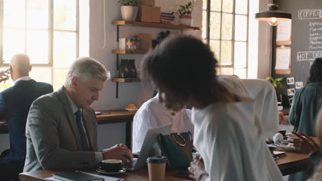 diverse-business-people-working-in-cafe-bustling-with-activity-drinking-coffee-relaxing-on-lunch-using-technology-in-busy-restaurant