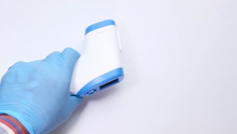 handheld non-contact thermometer in a blue glove