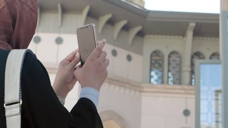 woman in hijab taking a picture of a mosque