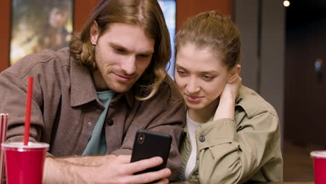 pareja feliz usando teléfono móvil en el cine