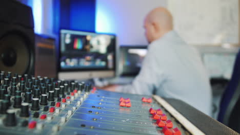 un hombre que trabaja en un estudio de grabación como editor de video y audio con mesa de mezclas y computadoras