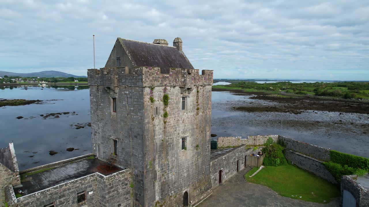 Drone orbits over Dunguaire Castle tower in Galway with scenic landscape