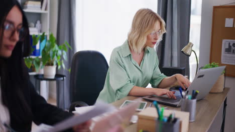 woman with glasses working on laptop in office