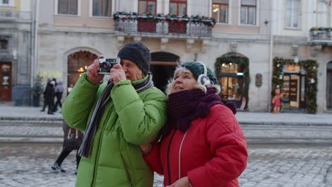 grandfather taking photo pictures with grandmother on retro camera in winter snowy town lviv ukraine