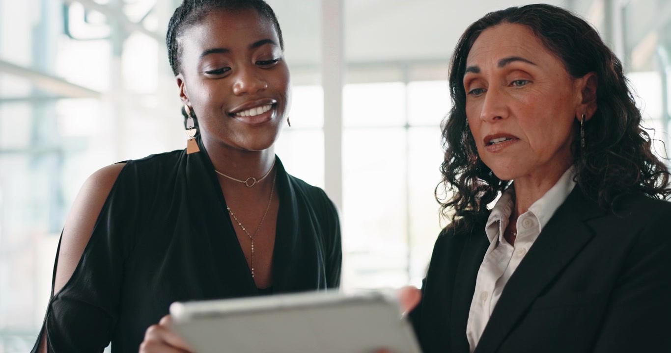 Two Businesswomen Collaborating on a Tablet in a Modern Office