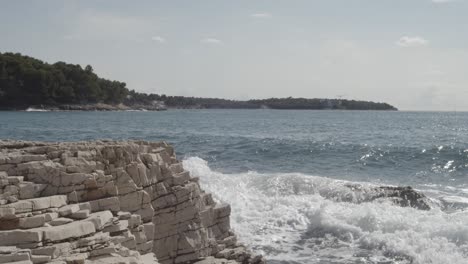 strong waves of the adriatic sea crashing against rocks and stones on coastline during summer