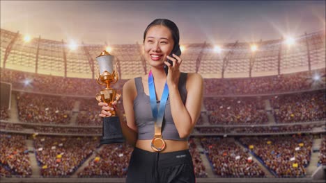 Asian Woman With A Gold Medal Holding A Gold Trophy And Talking On Smartphone At The Stadium