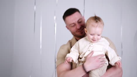 beautiful caucasian baby in hands of his proud dad. happy father and son portrait in studio.